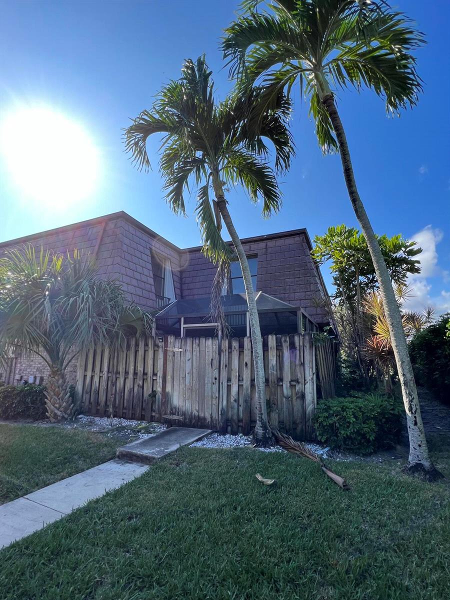 A two-story building with a wooden fence, a screened patio, and palm trees in front — 7482 E Courtyard Run E, Boca Raton FL 33433, BOCA RATON, FL