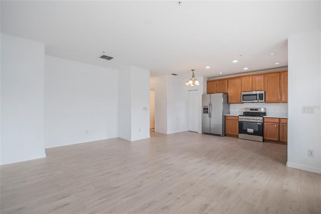 An open-concept kitchen with wood cabinets and stainless steel appliances overlooks a spacious living area — 2018 CYPRESS BAY BOULEVARD, KISSIMMEE, FL