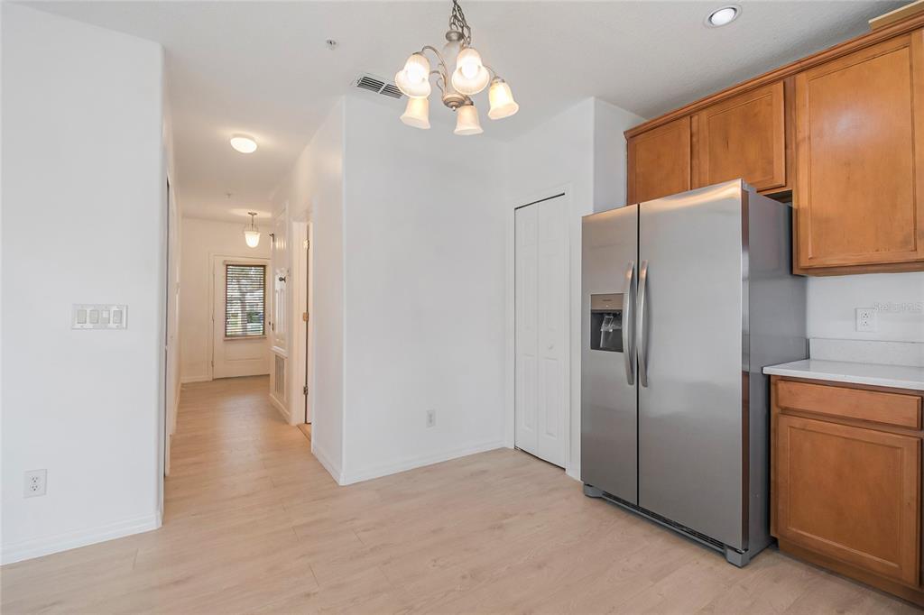 A kitchen area features light wood-look flooring, a stainless steel refrigerator, and a chandelier — 2018 CYPRESS BAY BOULEVARD, KISSIMMEE, FL