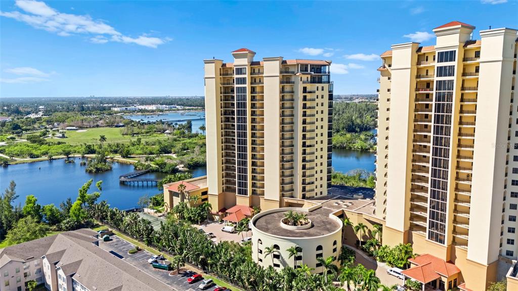 An aerial view shows two tall, tan residential towers next to a lake and parking lot — 14380 RIVA DEL LAGO DRIVE UNIT 1804, FORT MYERS, FL