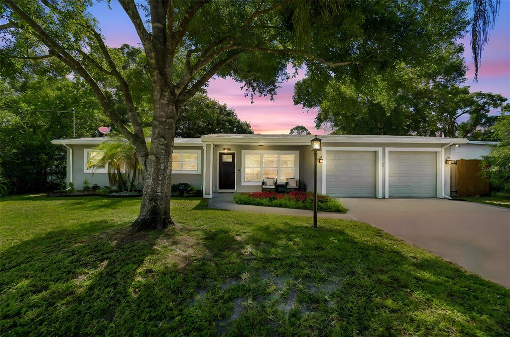 A single-story gray house with a covered entryway, attached garage, and a large front lawn — 12417 N ROME AVENUE, TAMPA, FL