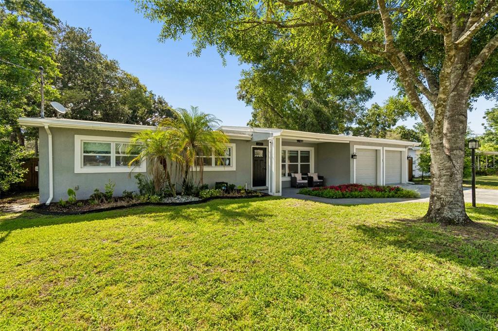 A single-story house exterior features a covered front porch, a black door, and landscaping — 12417 N ROME AVENUE, TAMPA, FL
