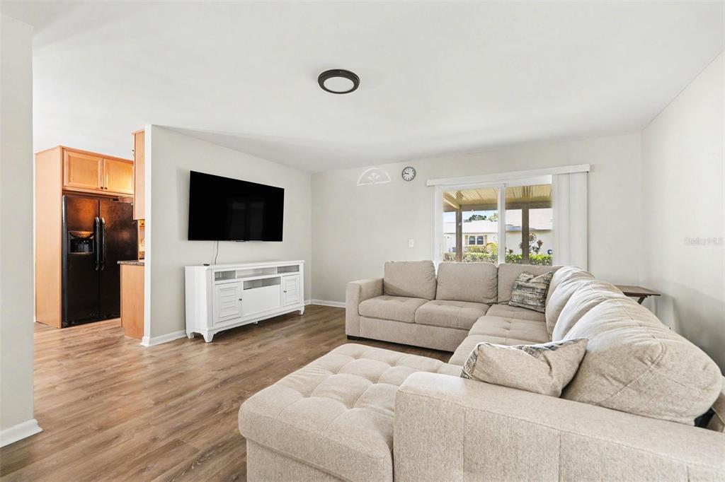 A living room features light wood flooring, a beige sectional sofa, and a wall-mounted television — 3267 39TH STREET S UNIT B, ST PETERSBURG, FL
