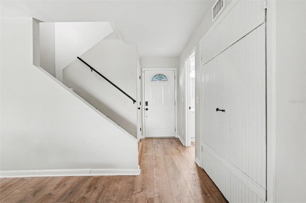 A bright entryway features wood-look flooring, a white staircase with a black railing, and doors — 3267 39TH STREET S UNIT B, ST PETERSBURG, FL