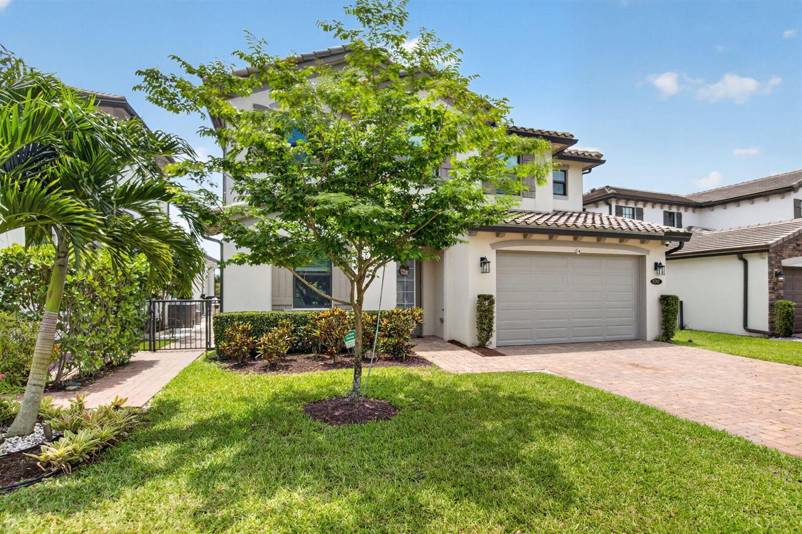 A two-story suburban house with a paved driveway, a garage, and a front yard tree — 8787 Grand Prix Lane, Boynton Beach FL 33472, BOYNTON BEACH, FL