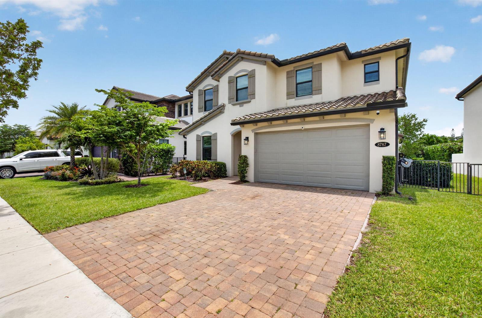 A two-story stucco house with a paved driveway, a two-car garage, and a tiled roof — 8787 Grand Prix Lane, Boynton Beach FL 33472, BOYNTON BEACH, FL