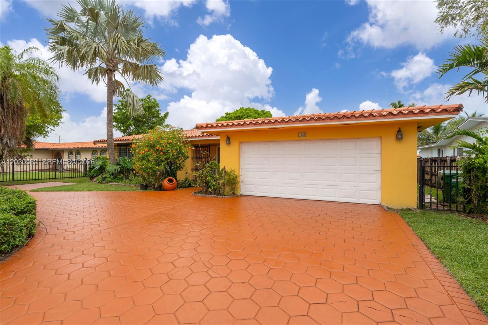 A yellow house with a tiled roof and a paved driveway sits under a blue sky — 1320 SW 84th Ave, Miami FL 33144, MIAMI, FL