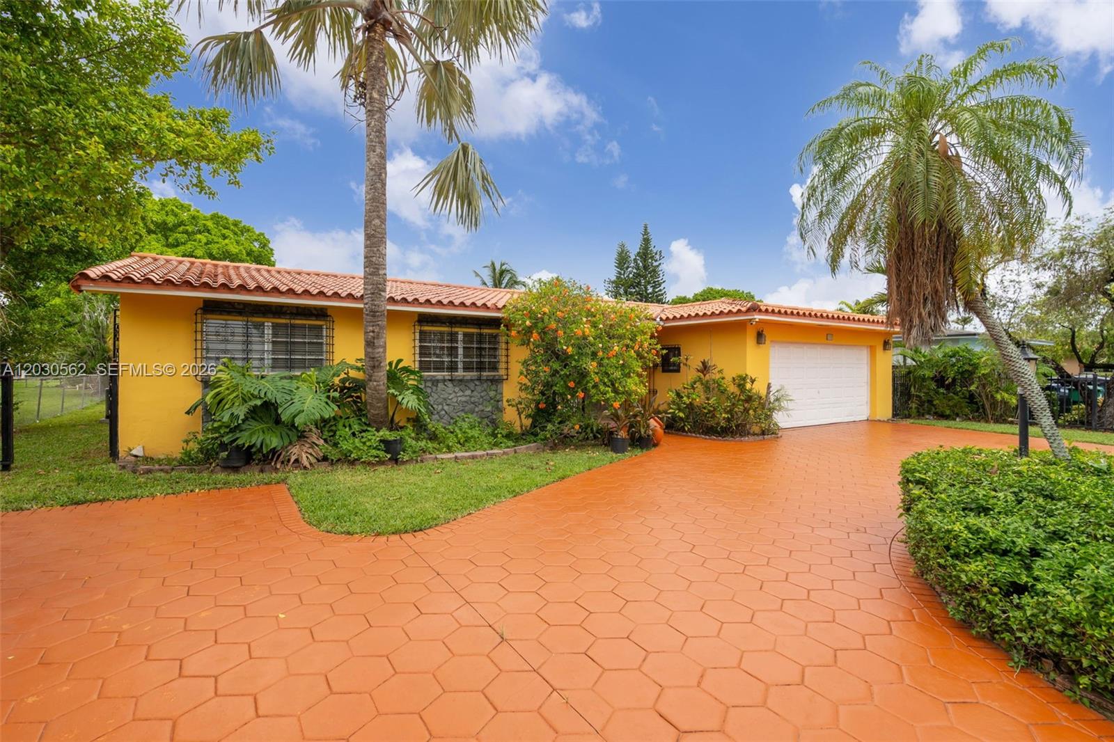 A yellow single-story house features a terracotta tile roof and a patterned orange driveway — 1320 SW 84th Ave, Miami FL 33144, MIAMI, FL