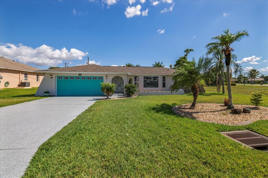 A single-story house with a teal garage door, a concrete driveway, and palm trees — 206 SE 45TH TERRACE, CAPE CORAL, FL