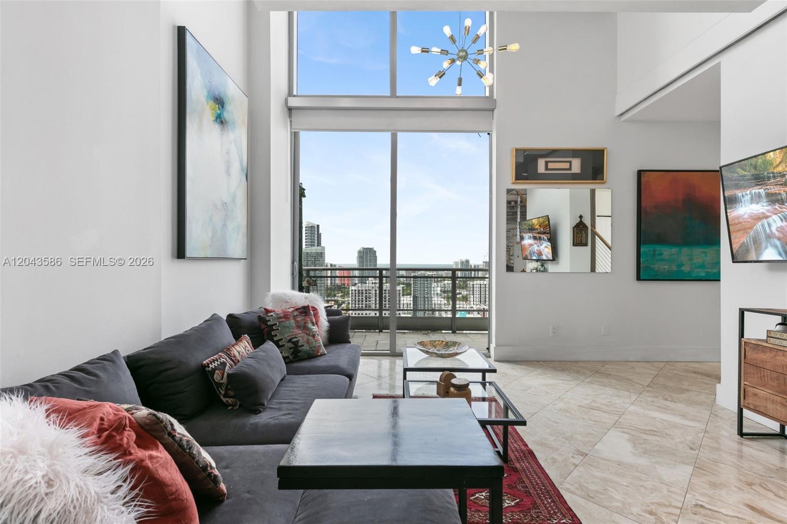 A modern living room features a double-height window, tile flooring, and a city balcony view — 690 SW 1st Ct, Miami FL 33130, MIAMI, FL