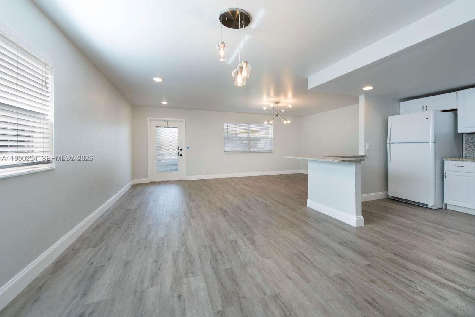 An open-concept living and kitchen area features light gray flooring and white cabinetry — 494 Monaco K # 494, Delray Beach FL 33446, DELRAY BEACH, FL