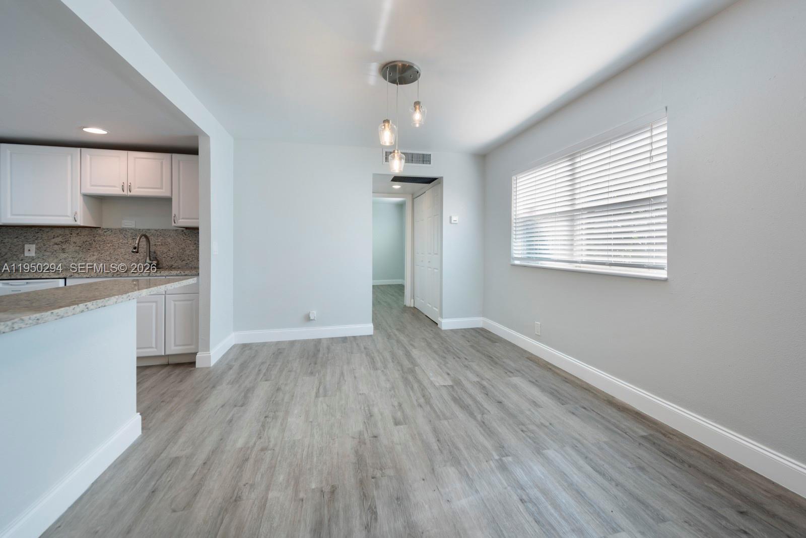 This dining area features light gray walls, wood-look flooring, and a modern three-light pendant fixture — 494 Monaco K # 494, Delray Beach FL 33446, DELRAY BEACH, FL