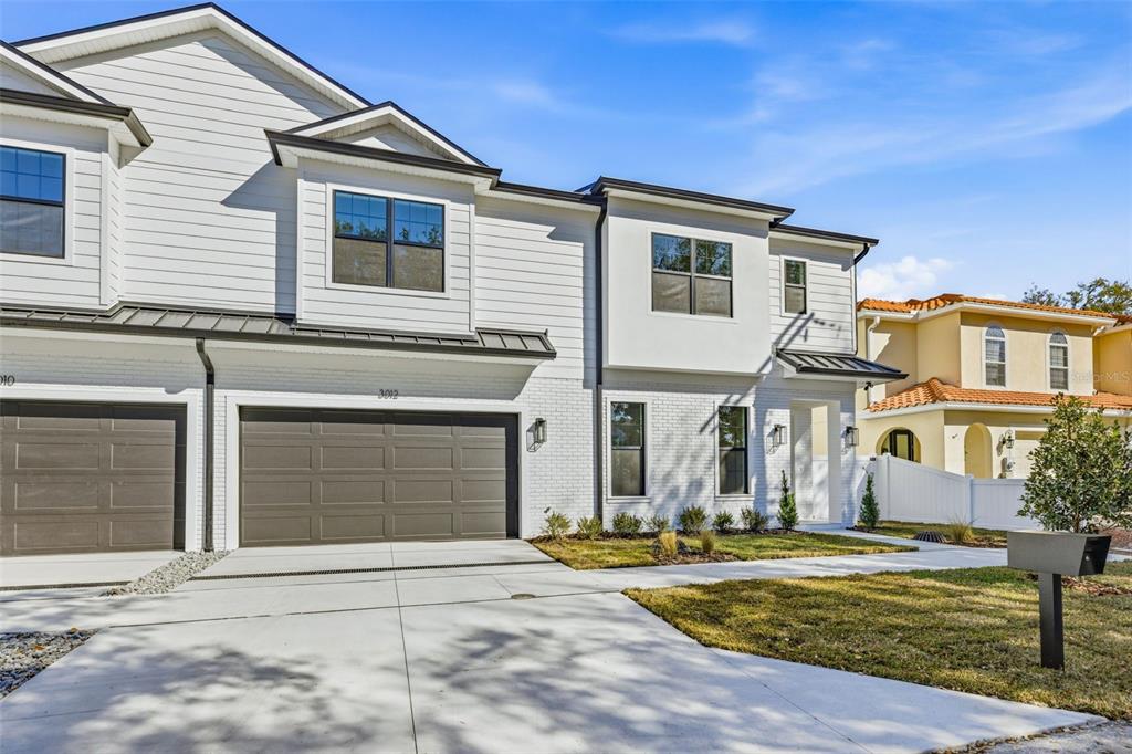 A modern two-story townhouse with white siding, brick accents, and a two-car garage — 3012 S ESPERANZA AVENUE, TAMPA, FL