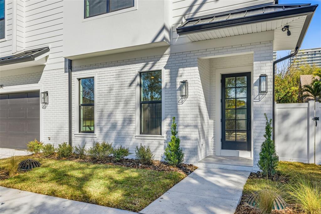 A white brick exterior features black window frames, a front door, and a concrete walkway — 3012 S ESPERANZA AVENUE, TAMPA, FL