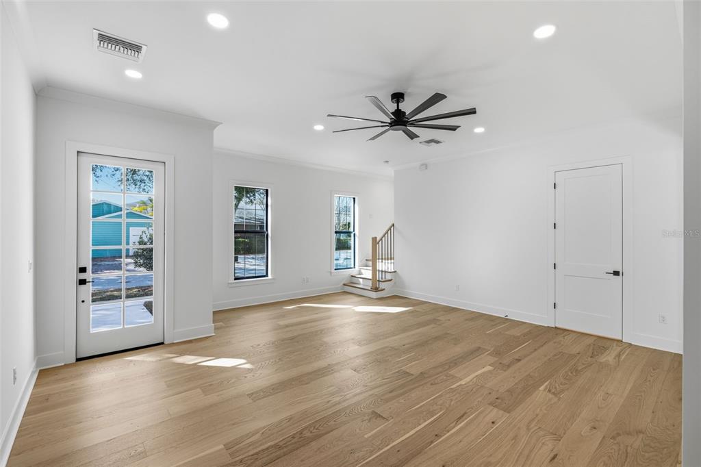 A bright, empty room features light wood flooring, white walls, a ceiling fan, and a door — 3012 S ESPERANZA AVENUE, TAMPA, FL