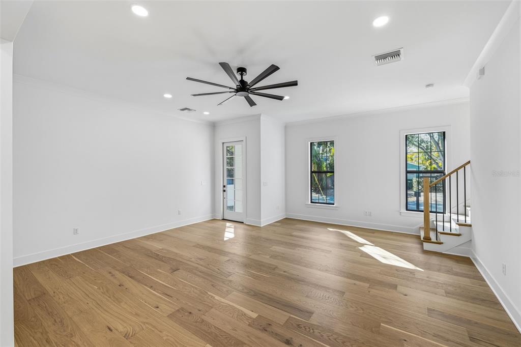 An empty room with white walls, hardwood floors, a ceiling fan, and a staircase — 3012 S ESPERANZA AVENUE, TAMPA, FL