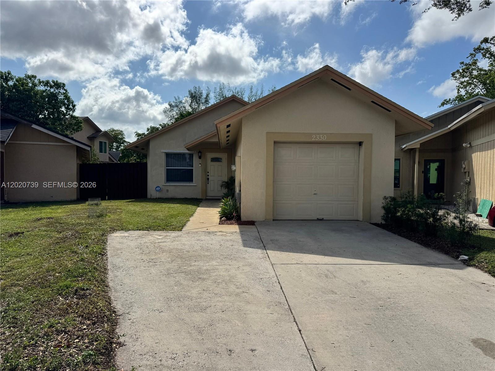 A single-story house with a beige stucco exterior, a one-car garage, and a concrete driveway — 2330 SW 80th Ter, Miramar FL 33025, MIRAMAR, FL