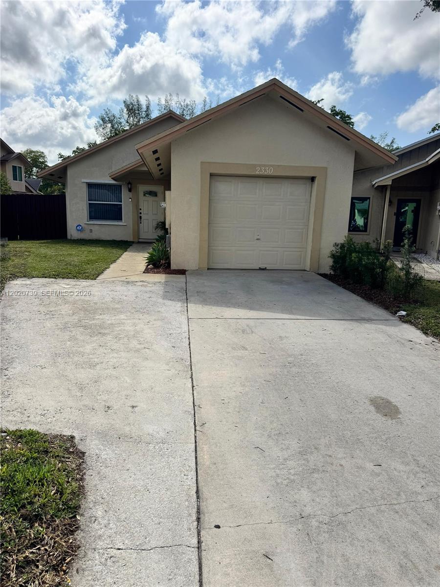 A single-story house with a beige stucco exterior, a one-car garage, and a concrete driveway — 2330 SW 80th Ter, Miramar FL 33025, MIRAMAR, FL
