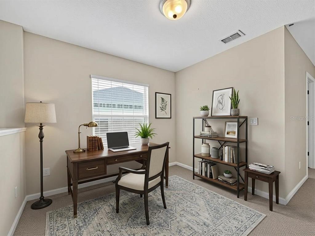 A home office features a wooden desk, a bookshelf, and a patterned rug on carpet — 10411 PARK COMMONS DRIVE, ORLANDO, FL