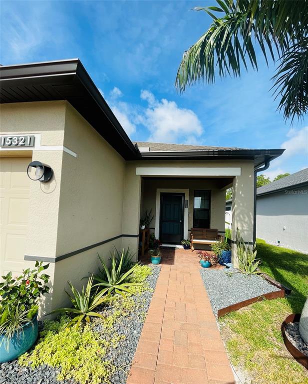 A beige house exterior features a brick walkway leading to a covered front entryway — 15321 MILLE FIORE BOULEVARD, PORT CHARLOTTE, FL