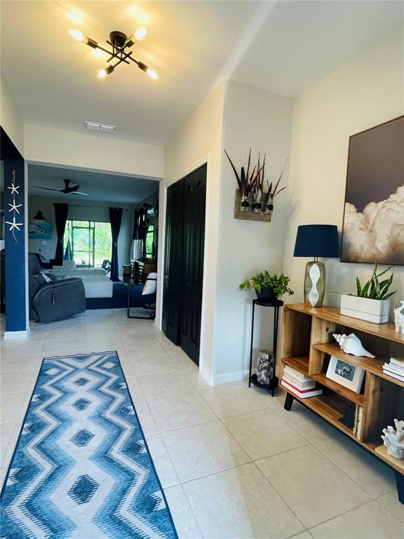 A tiled entryway features a geometric runner, a wooden console table, and a modern light fixture — 15321 MILLE FIORE BOULEVARD, PORT CHARLOTTE, FL