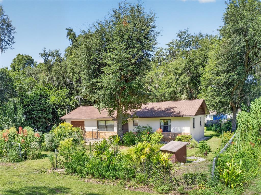 A single-story house with a brown roof sits behind a fenced yard with lush landscaping — 1912 SE 169TH COURT, SILVER SPRINGS, FL