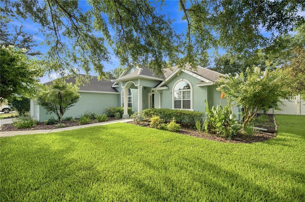 A light green single-story house with a front porch, arched window, and landscaped lawn — 5898 SW 89TH PLACE, OCALA, FL