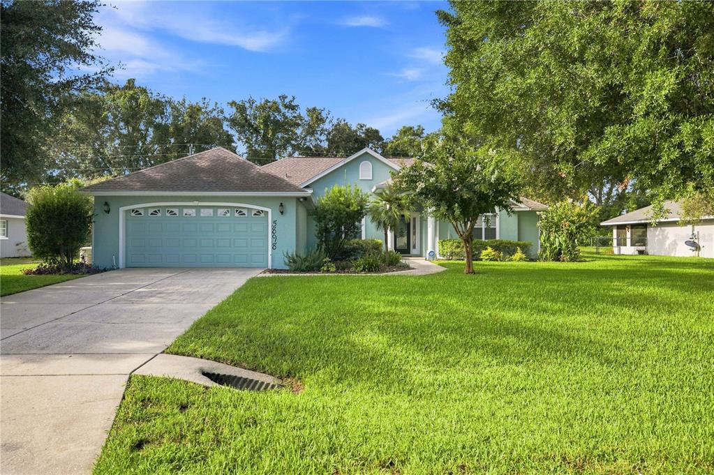 A light green single-story house with a two-car garage and a large front lawn — 5898 SW 89TH PLACE, OCALA, FL