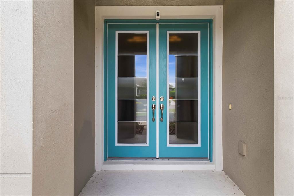 A set of double front doors with teal frames and rectangular glass panels — 7526 PARADISO DRIVE, APOLLO BEACH, FL