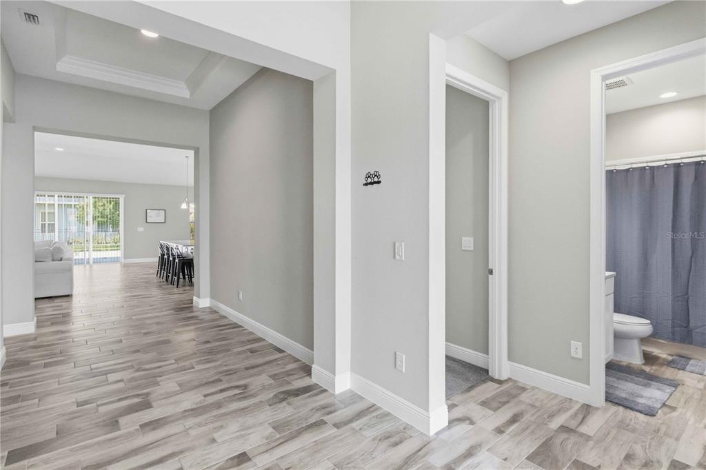 A hallway with light wood-look tile flooring leads to a living area and bathroom — 7526 PARADISO DRIVE, APOLLO BEACH, FL