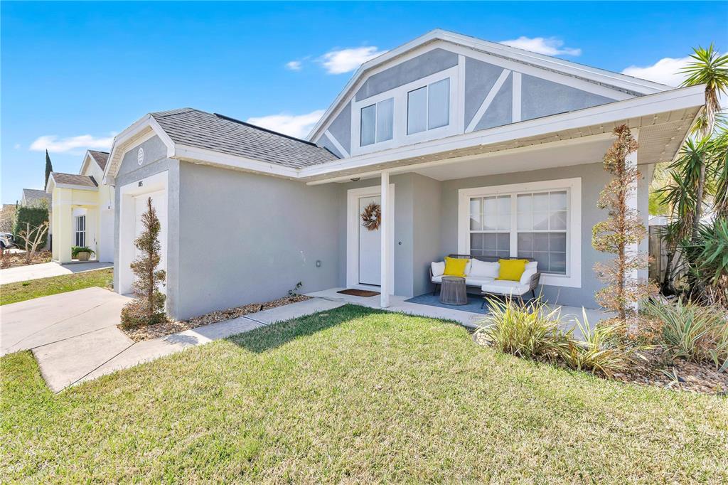 A single-story house with a gray stucco exterior, a covered front porch, and a lawn — 805 BELVOIR DRIVE, DAVENPORT, FL