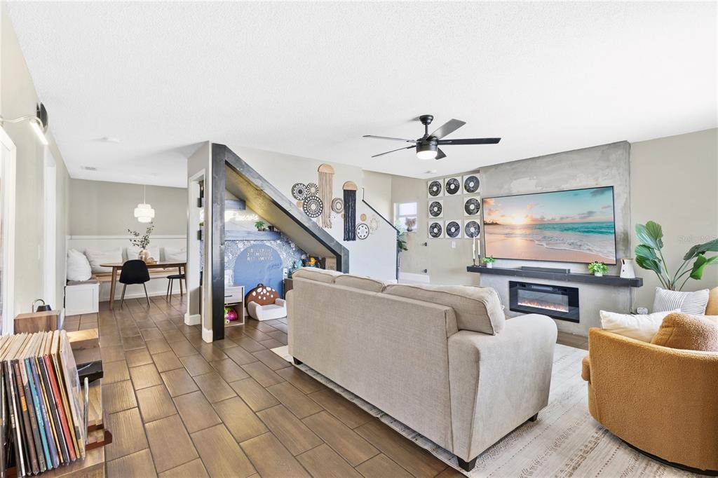 A living room with a fireplace, a large television, and an adjacent dining area — 805 BELVOIR DRIVE, DAVENPORT, FL