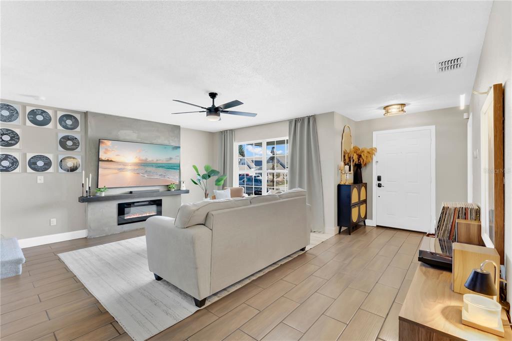 A living room features a fireplace, a television, a sofa, and vinyl record wall decor — 805 BELVOIR DRIVE, DAVENPORT, FL