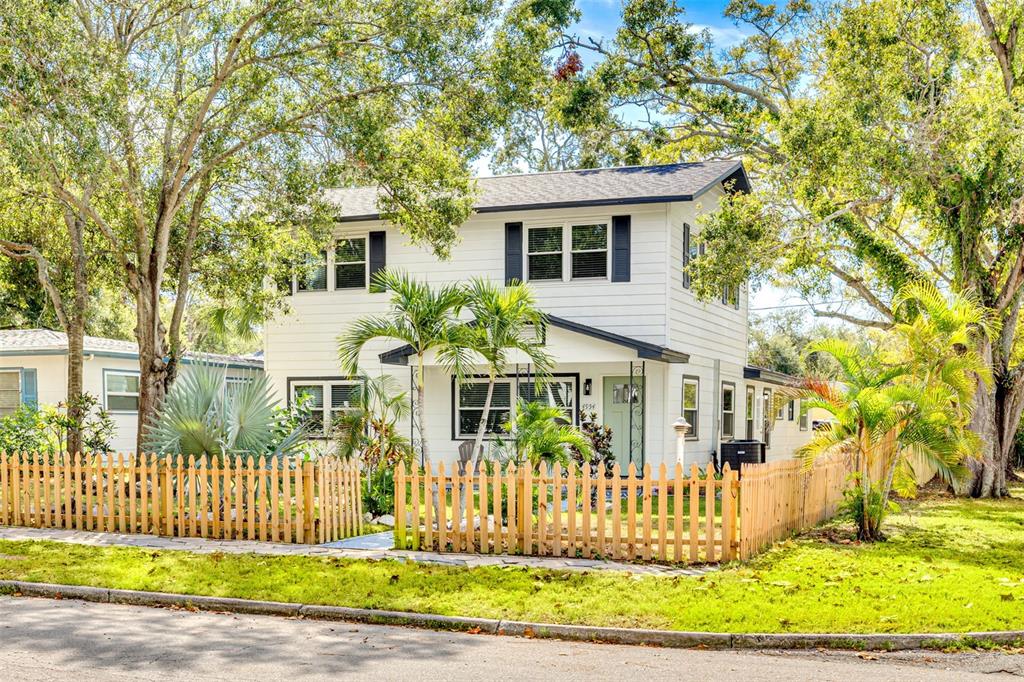 A two-story white house with dark shutters and a wooden picket fence in the front — 4954 2ND AVENUE N, ST PETERSBURG, FL