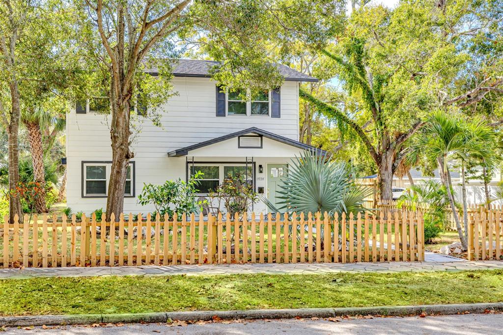 A two-story white house with a picket fence and a front porch sits behind trees — 4954 2ND AVENUE N, ST PETERSBURG, FL