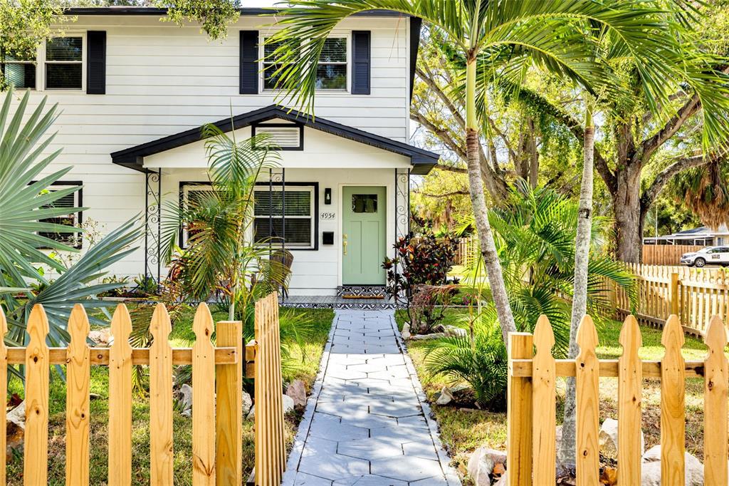 A two-story white house with a light green front door and a wooden picket fence — 4954 2ND AVENUE N, ST PETERSBURG, FL