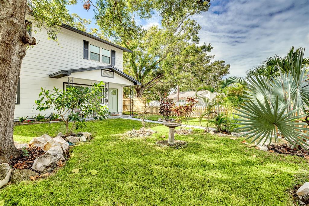 A two-story white house with a front porch, lawn, and various trees and plants — 4954 2ND AVENUE N, ST PETERSBURG, FL