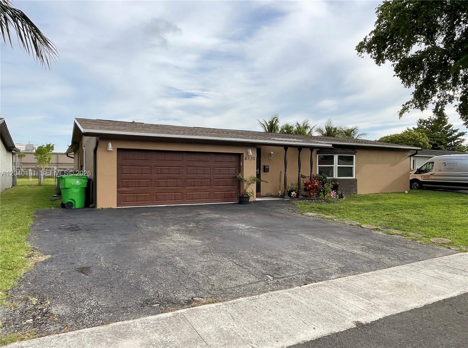 A single-story house with a brown garage door, tan exterior, and a paved driveway — 8330 NW 20th Ct, Sunrise FL 33322, SUNRISE, FL
