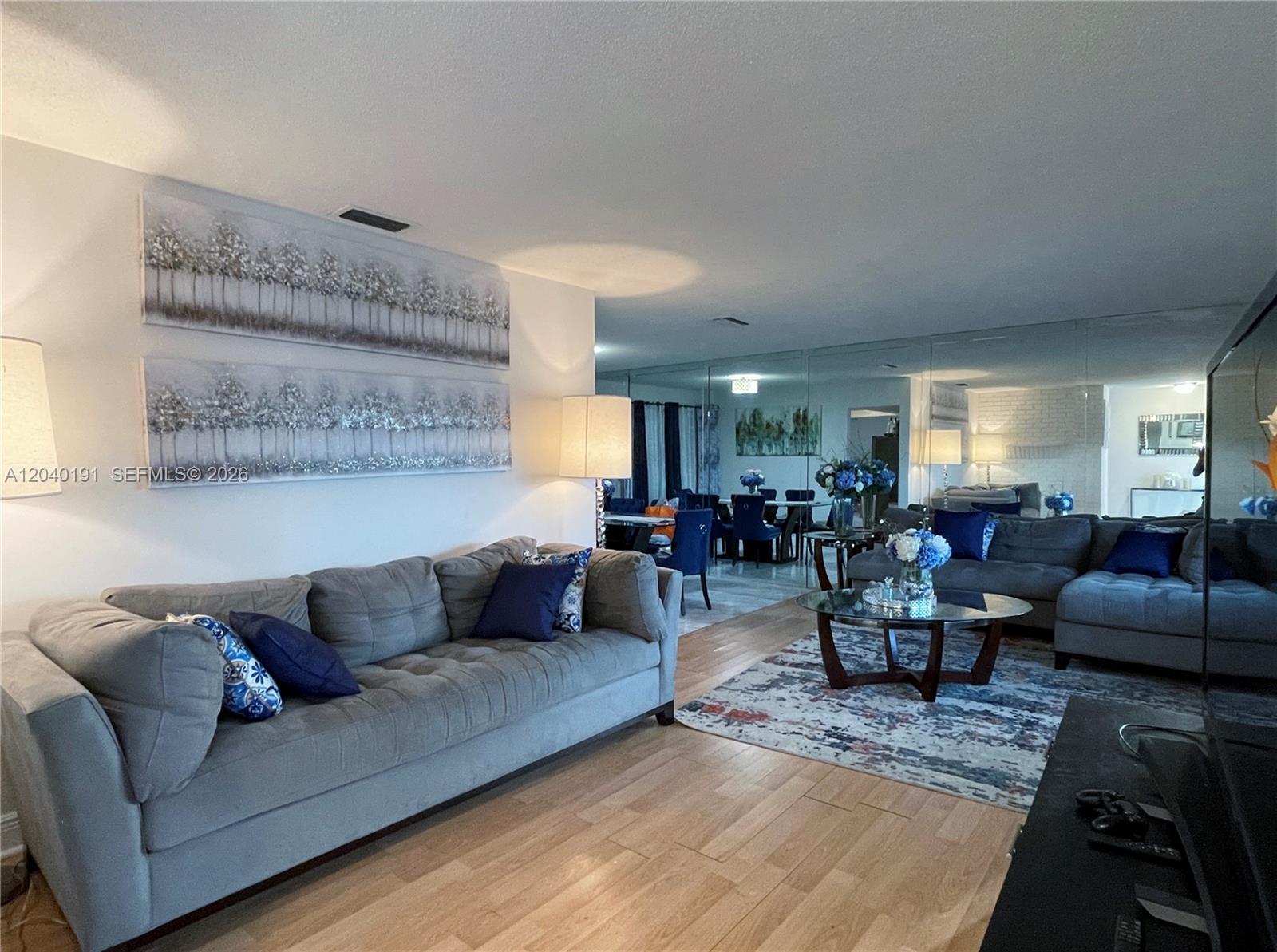 A living room features a gray sectional sofa, a glass coffee table, and mirrored walls — 8330 NW 20th Ct, Sunrise FL 33322, SUNRISE, FL