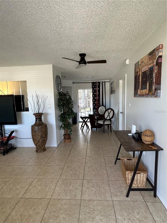 A living area with tile floors, a ceiling fan, and a dining space in the back — 7808 OSTEEN ROAD, NEW PORT RICHEY, FL