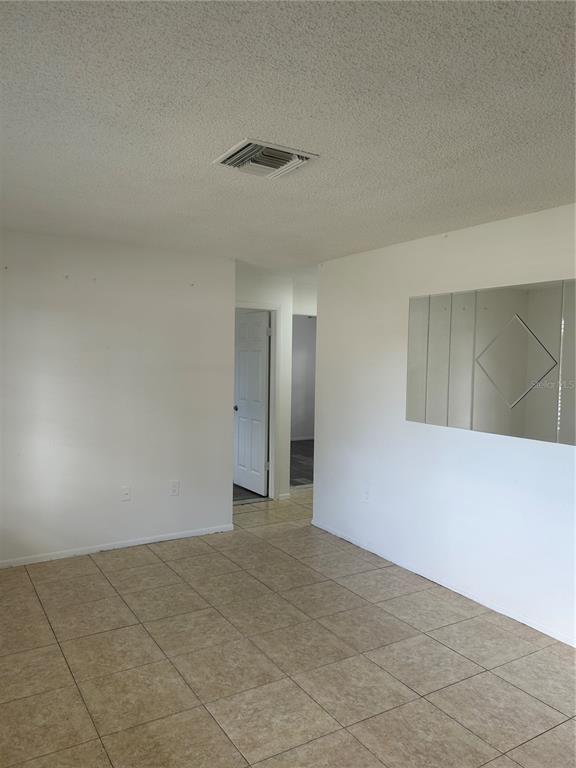 An interior view of a room with tiled floors, white walls, and a decorative wall mirror — 7808 OSTEEN ROAD, NEW PORT RICHEY, FL