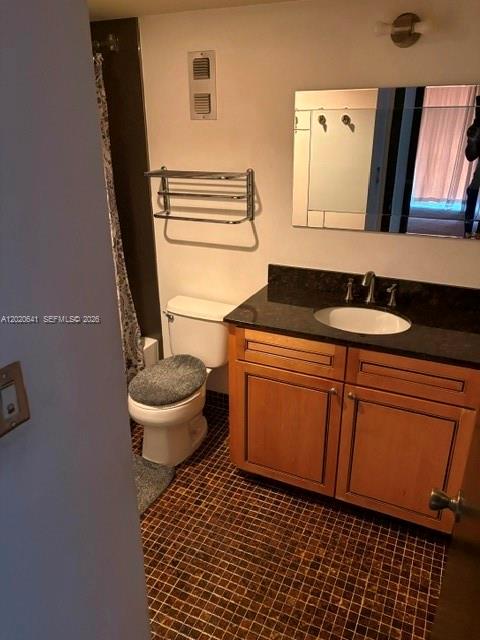 A bathroom features a wooden vanity with a dark countertop, a toilet, and tiled flooring — 2781 Taft St # 411, Hollywood FL 33020, HOLLYWOOD, FL
