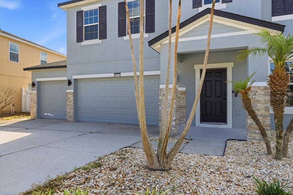 A two-story house exterior features a three-car garage, stone accents, and a front entryway — 9012 ORANGE BLOSSOM LOOP, HAINES CITY, FL