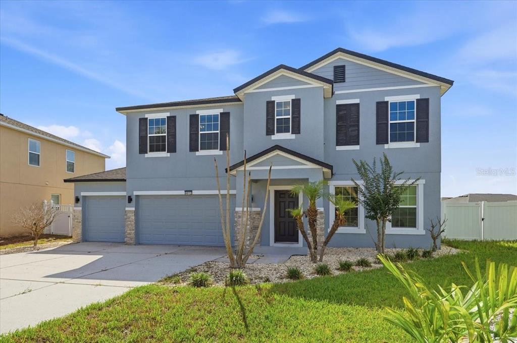 A two-story blue house with a three-car garage and a front yard — 9012 ORANGE BLOSSOM LOOP, HAINES CITY, FL