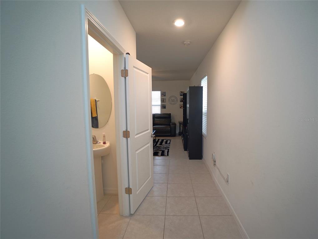 A hallway leads to a living area, with a half bathroom visible through an open door — 9904 CALYPSO ORCHID COURT, RIVERVIEW, FL
