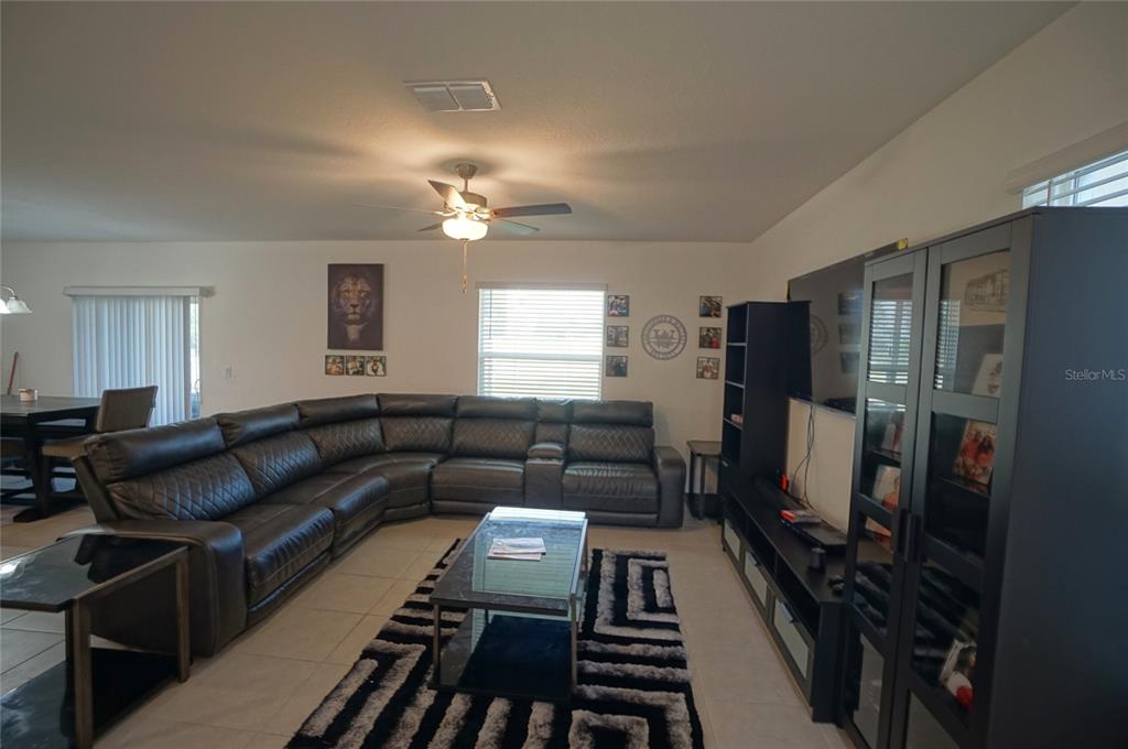 A living room features a large gray sectional sofa, a patterned rug, and dark furniture — 9904 CALYPSO ORCHID COURT, RIVERVIEW, FL
