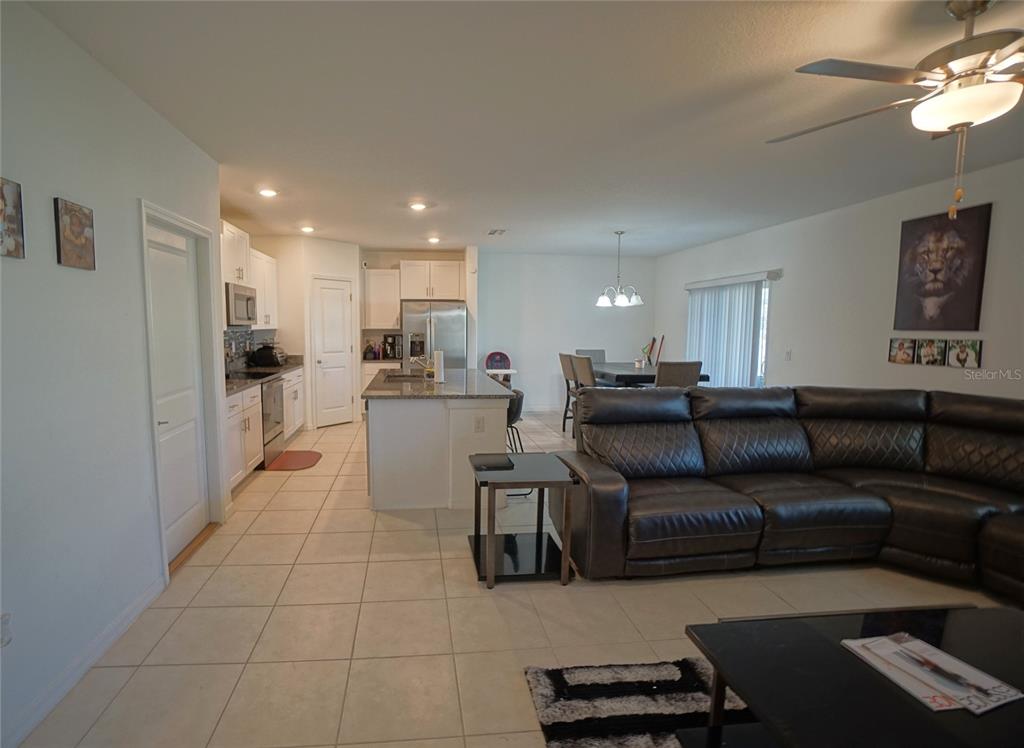An open-concept kitchen and living area features tile flooring, a kitchen island, and leather furniture — 9904 CALYPSO ORCHID COURT, RIVERVIEW, FL