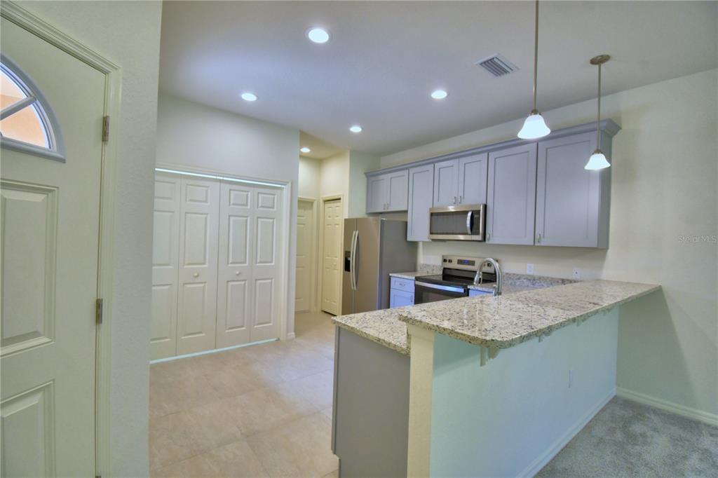 A kitchen features light gray cabinets, granite countertops, stainless steel appliances, and a breakfast bar — 1709 LINZ CT, WINTER HAVEN, FL