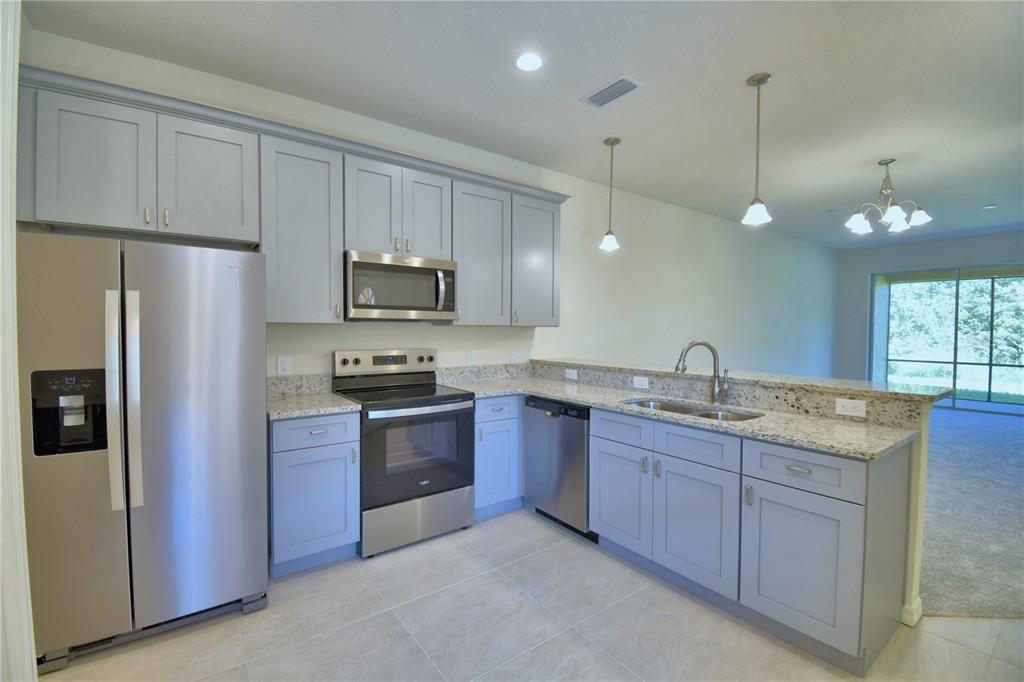 A kitchen with gray cabinets, stainless steel appliances, and granite countertops — 1709 LINZ CT, WINTER HAVEN, FL