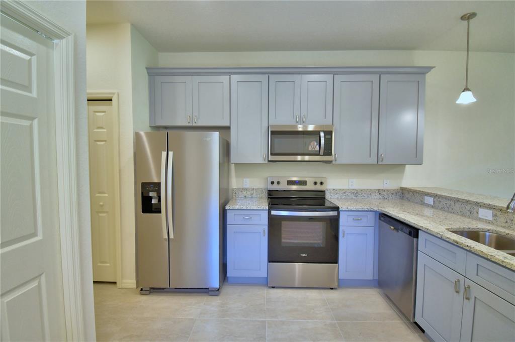 A kitchen features grey cabinets, stainless steel appliances, and granite countertops — 1709 LINZ CT, WINTER HAVEN, FL